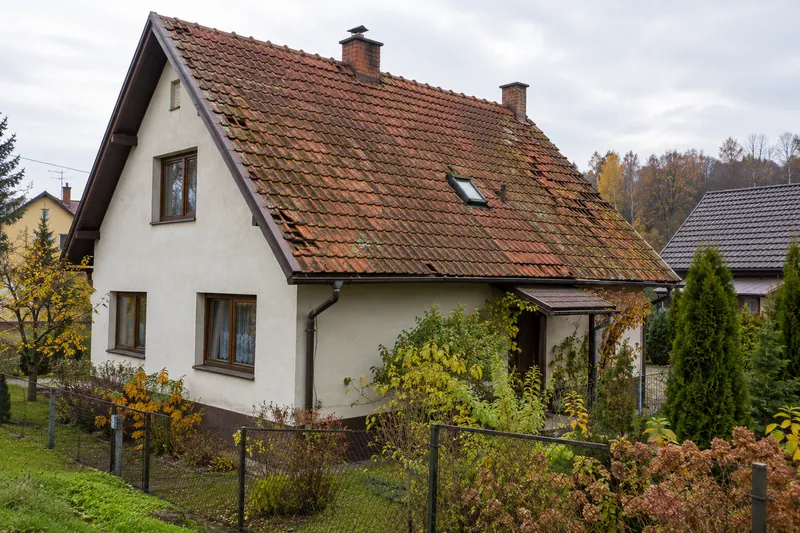 Dom z poddaszem i starą, omszałą czerwoną dachówką