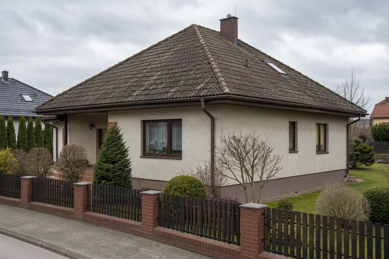 Dom z czterospadowym dachem pokrytym wyblakłą dachówką betonową