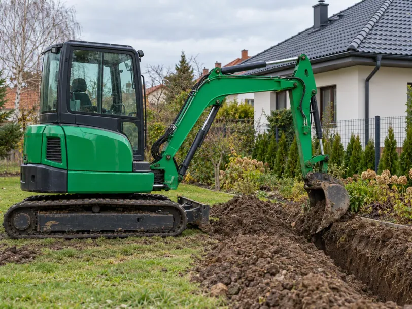 Zielona minikoparka kopie wąski rów w ogrodzie przy domu